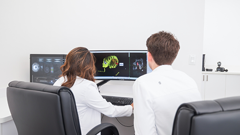 Two dentists looking at images of teeth on a computer