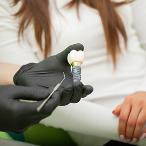 Dentist showing a dental implant model to a patient