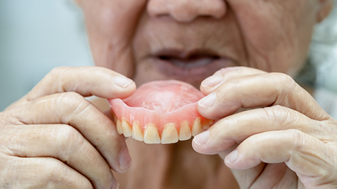 Senior placing a denture in their mouth