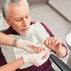 Senior dental patient being handed a denture