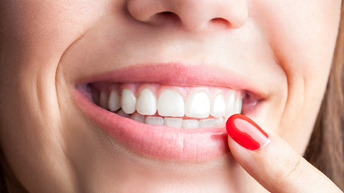 Close up of a person pointing to their flawless smile