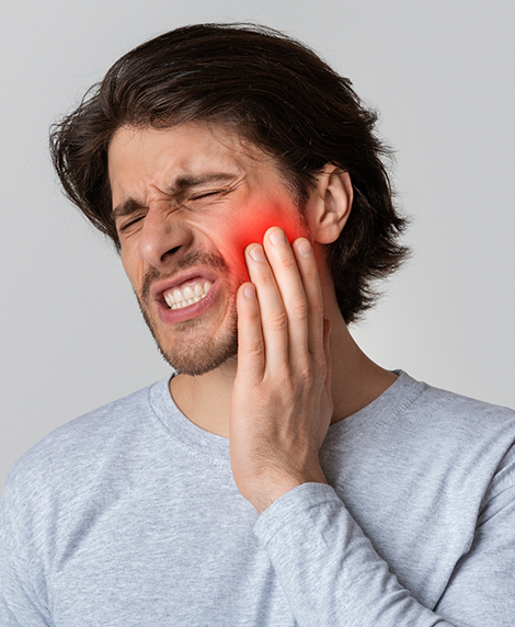 Man holding his cheek in pain before seeing an emergency dentist in Coral Springs