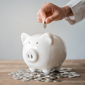 Person putting a coin into a piggy bank