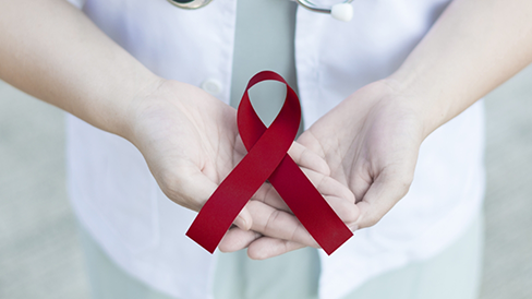 Dentist holding a red ribbon for oral cancer awareness