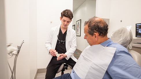 Doctor Daniyel showing a patient a model of the teeth