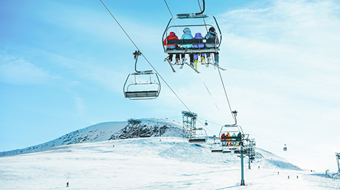 People riding a ski lift up a snowy mountain