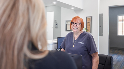 Dental team member at the front desk grinning at a patient