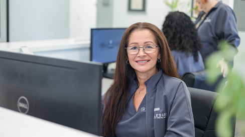 Dental team member sitting at a computer behind a desk