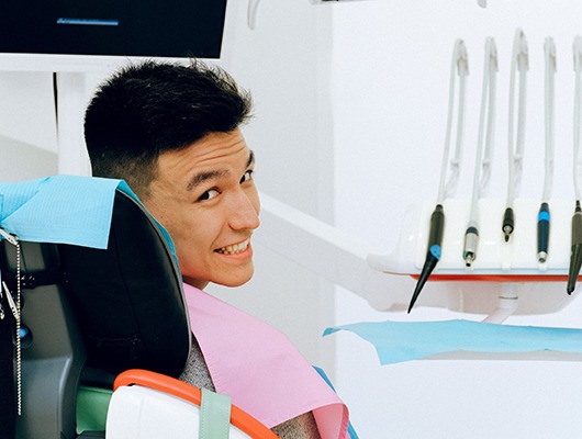 Man in dentist’s chair looking over his shoulder