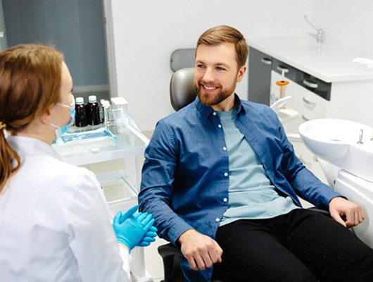 Male patient in treatment chair speaking to Guardian dentist