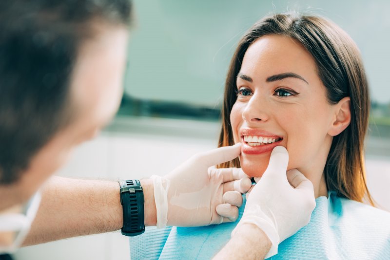 A dentist examining a young woman’s smile